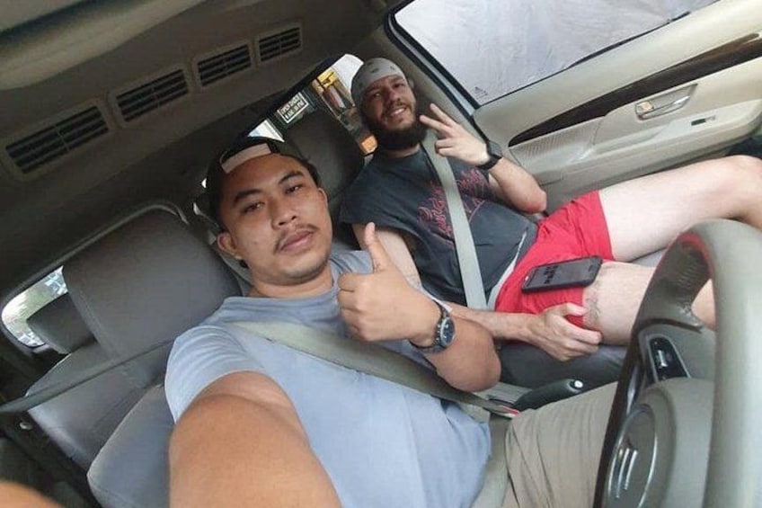 Due persone in auto, una indica il segno dell'ok con il pollice. 3
