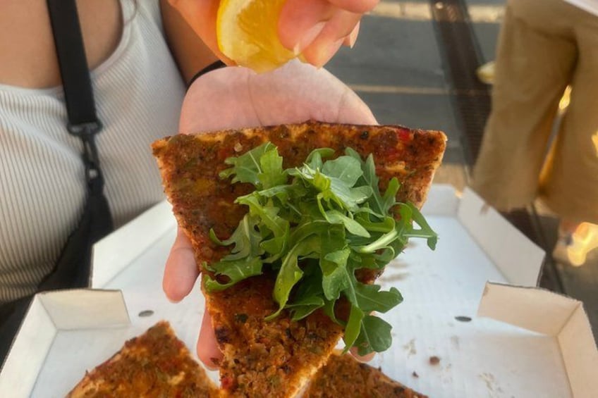 Une personne tenant une part de pizza garnie de légumes verts et une part d’orange. 4