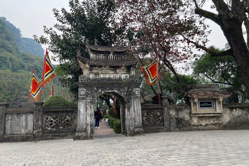 Una puerta tradicional adornada con banderas, un sendero y un paisaje montañoso de fondo. 2