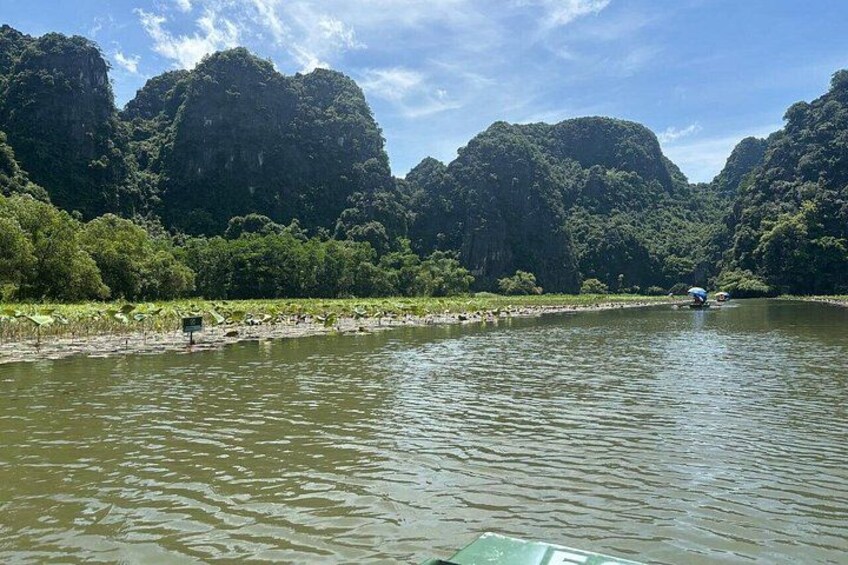 A river with a boat, surrounded by dense green forest and rocky cliffs. 4
