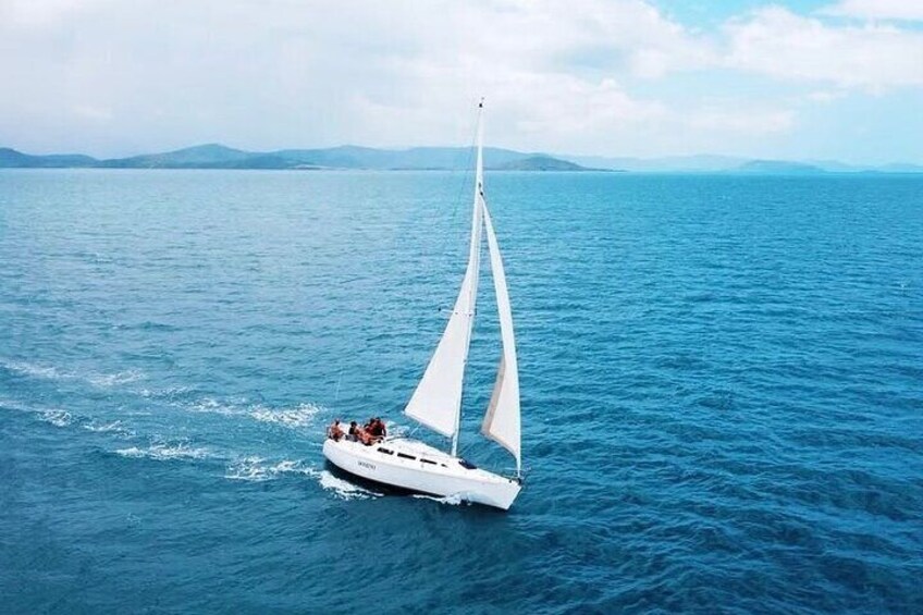 A sailboat with a white sail on a calm sea. 2