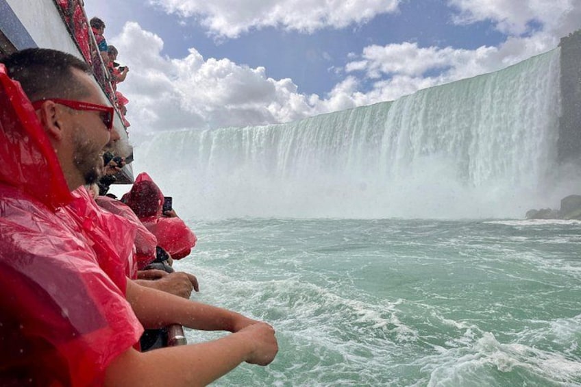 A large waterfall, people in red raincoats, and a boat in the water. 3