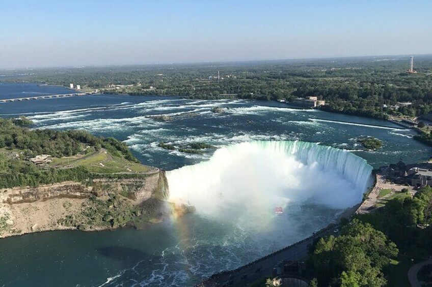 A large waterfall with a rainbow, surrounded by greenery and a river. 5