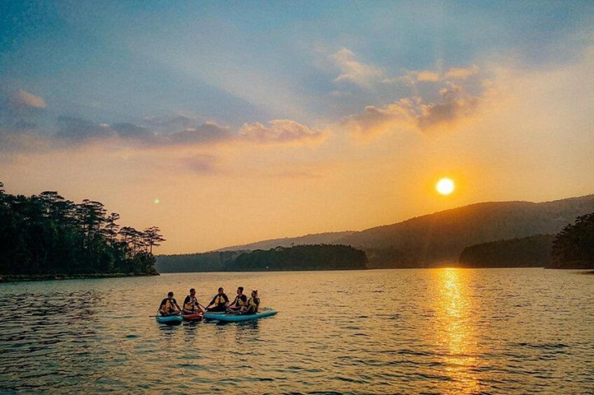 A sunset over a lake with a group of people in a canoe. 2