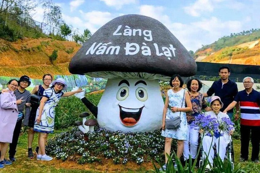 A group of people posing with a mushroom-shaped sculpture with Vietnamese text. 5