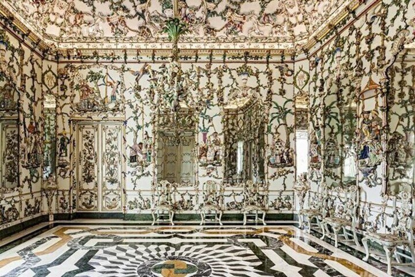 An ornate room with elaborate wall and ceiling decorations, a patterned floor, and classical furniture. 2