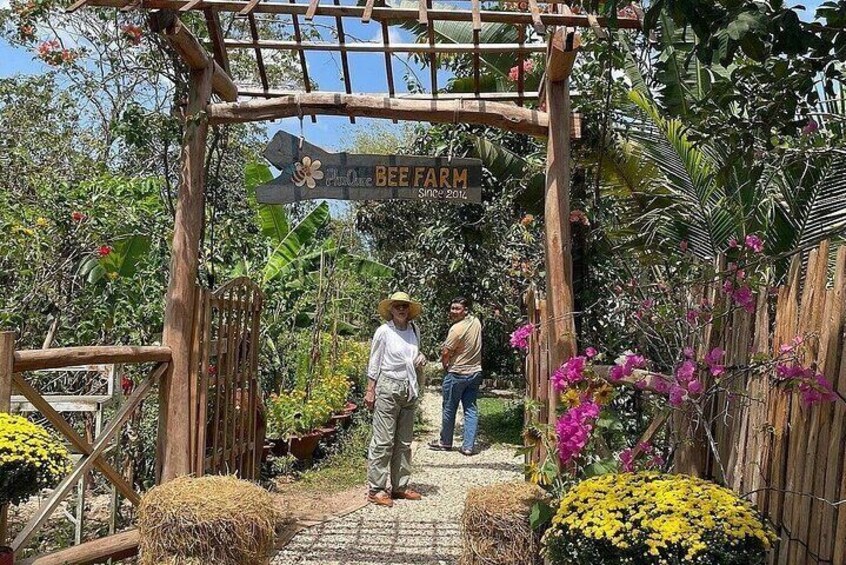 A wooden archway with a sign reading "Bee Farm" and a person walking through it. 4