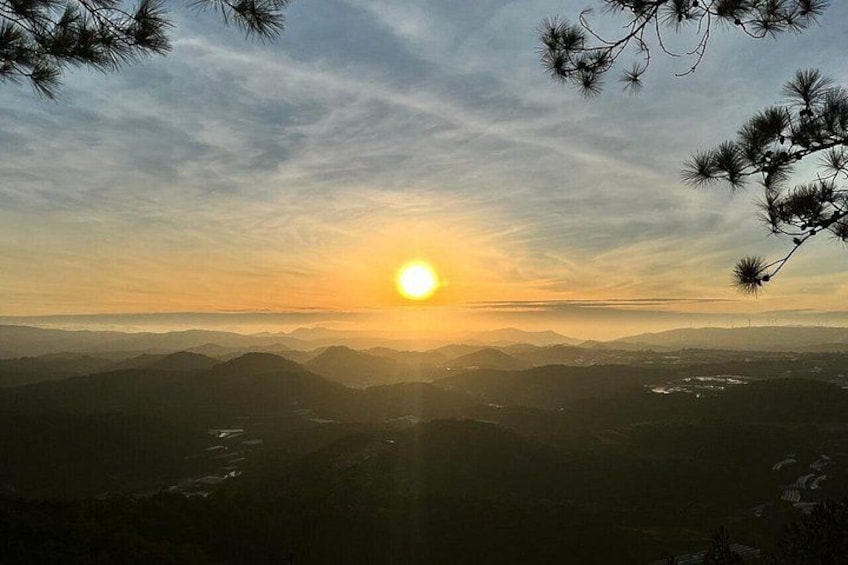 Un coucher de soleil sur un paysage montagneux, avec des pins au premier plan. 4