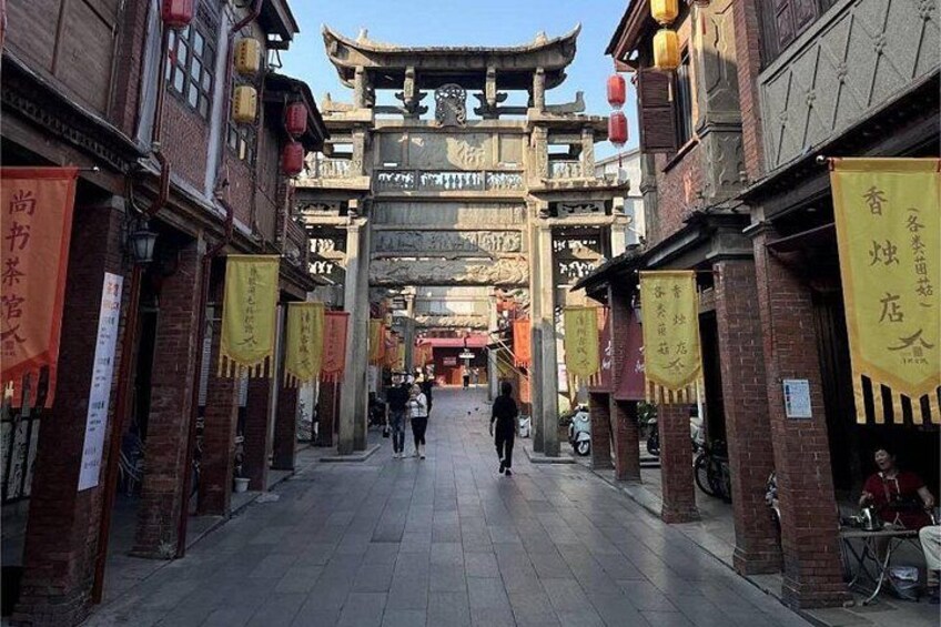 A traditional street with tiled pavement, brick buildings, and hanging yellow banners. 5