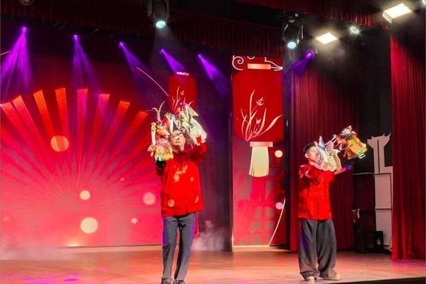 Two performers in red costumes on a stage with a red backdrop and a fan design. 3