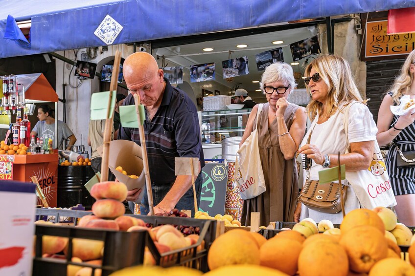 A fruit market with various fruits on display and people shopping. 5