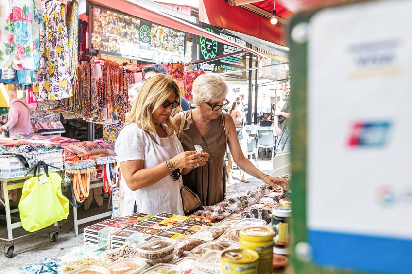 Two people at a market stall with various items for sale. 4