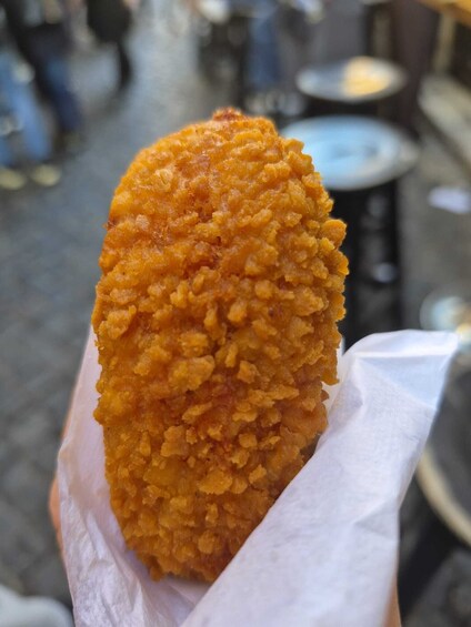 A hand holding a fried food item. 1