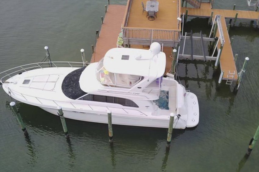 A white motorboat docked at a wooden pier with a covered seating area and a small table. 3