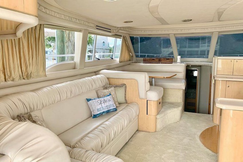 A boat interior with a cushioned seating area, a small table, and a window. 5