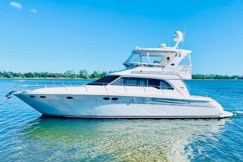 A white yacht on calm water with a clear sky and distant shoreline. 2