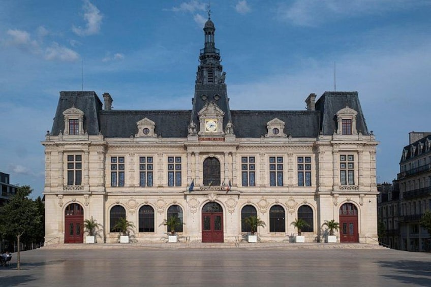 A historic building with a clock tower, arched windows, and red doors. 2