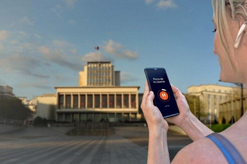 Una persona sosteniendo un teléfono inteligente con una aplicación de música abierta, de pie frente a un edificio con una cúpula y columnas. 5