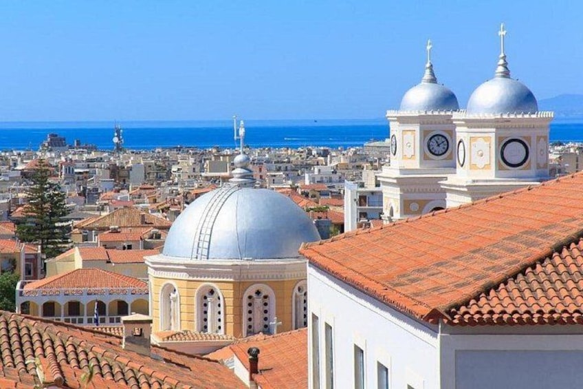 Un paisaje urbano costero con edificios de cúpulas destacadas y un cielo azul despejado. 3