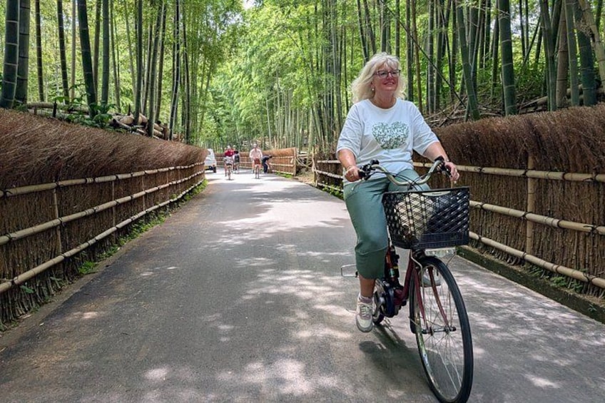 A person riding a bicycle on a paved path surrounded by bamboo trees. 1