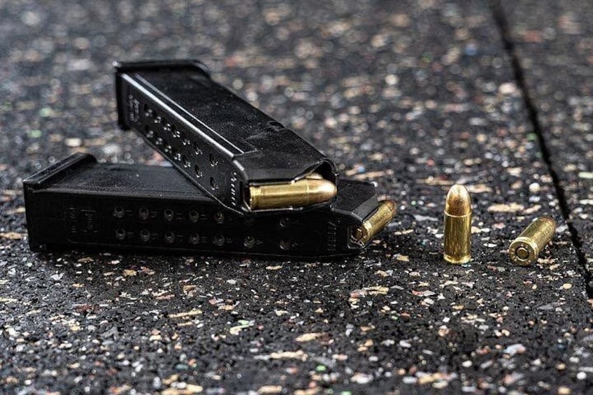 A handgun, bullets, and a magazine on a textured surface. 2