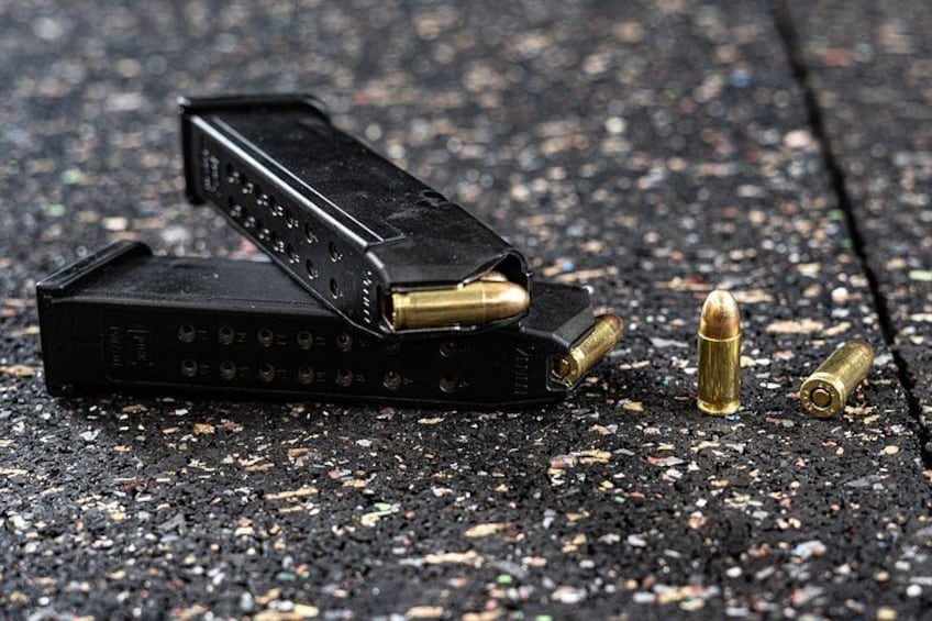 Una pistola, balas y un cargador sobre una superficie rugosa. 2