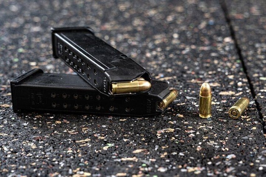 Un pistolet, des balles et un chargeur, posés sur une surface rugueuse. 3