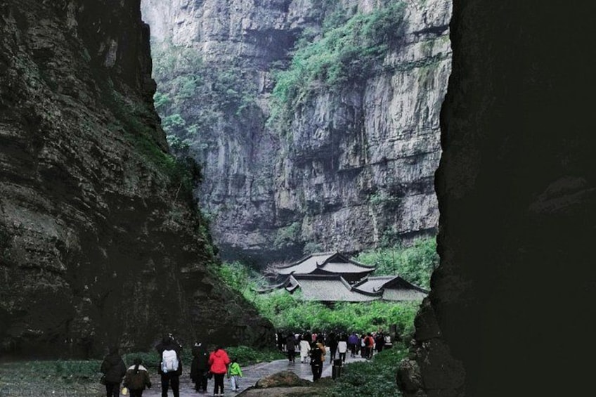 Un canyon au fond duquel se trouvent des bâtiments traditionnels, et où l’on voit des personnes se promener le long d’un sentier. 4