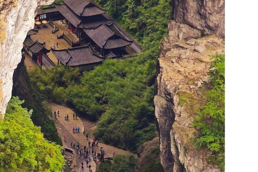 Un bâtiment traditionnel niché à flanc de falaise, entouré d’une végétation luxuriante. 2