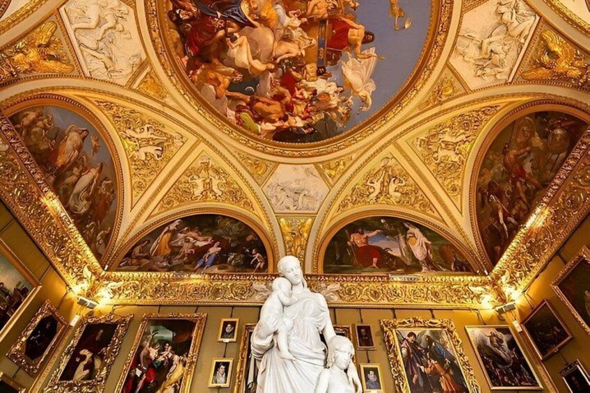 An ornate ceiling with frescoes and a central statue. 2