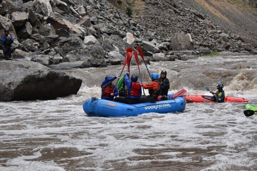 A group of people kayaking on a river with large rocks in the background. 2
