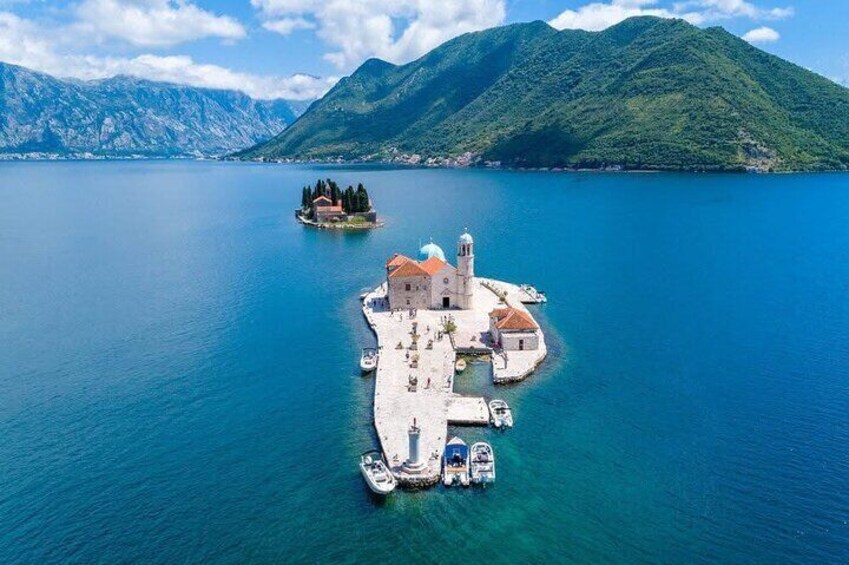 An aerial view of a coastal town with a prominent church, a small island with trees, and mountains in the background. 3