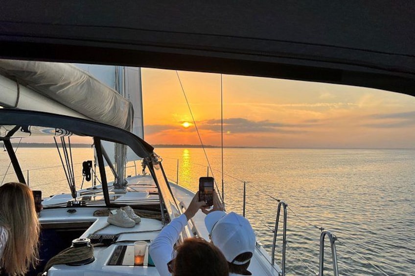 A sunset viewed from a sailboat with a person taking a photo. 2