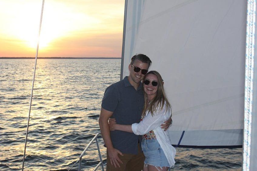 A couple on a sailboat with a sunset in the background. 5