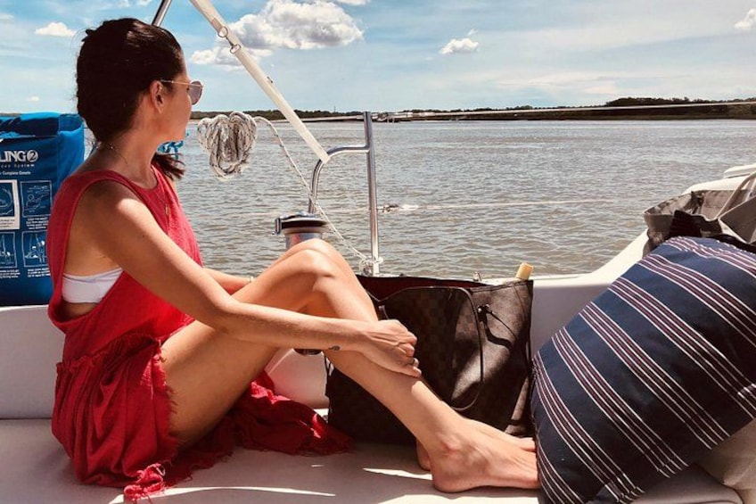 A person sitting on a boat with a water body and a distant shoreline in the background. 3