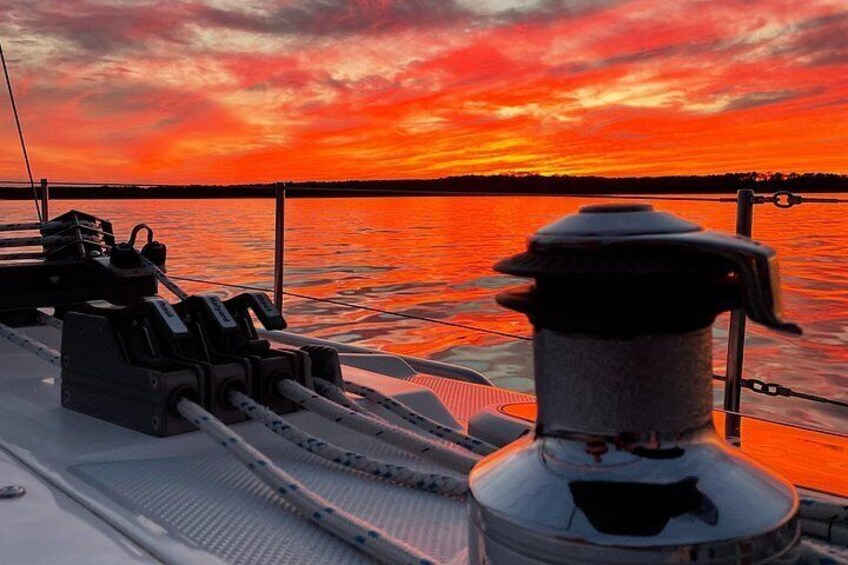 A boat deck with a water spout and a sunset over the water. 2