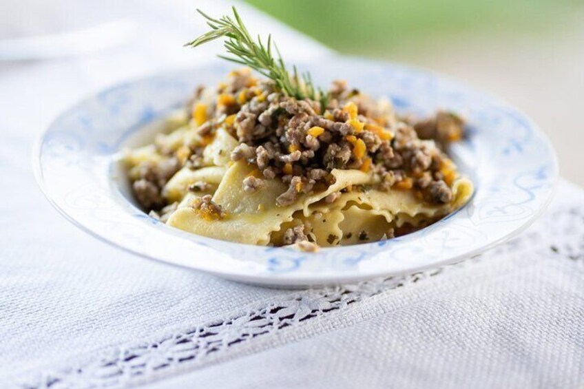 Een bord ravioli met gehakt vlees en een takje rozemarijn. 4