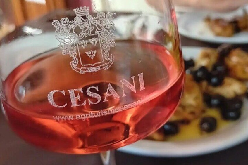 Een glas rode wijn met het label 'CESANI' en een familiewapen. 5