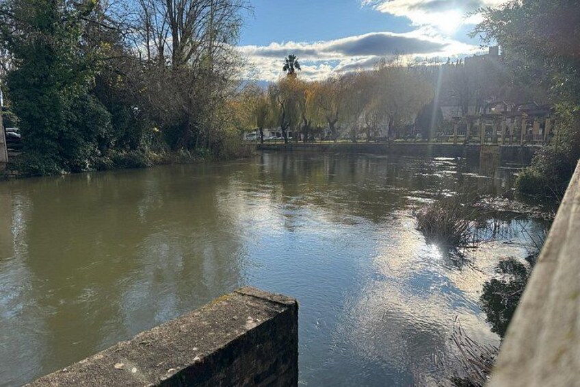 Une rivière paisible, avec un quai en bois, des arbres et un bâtiment visible au loin. 5