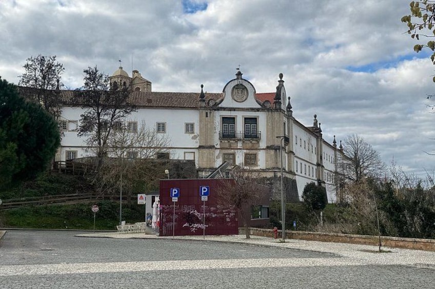 Un bâtiment historique doté d’une tour horloge, d’un espace de stationnement et d’une structure rouge en premier plan. 2