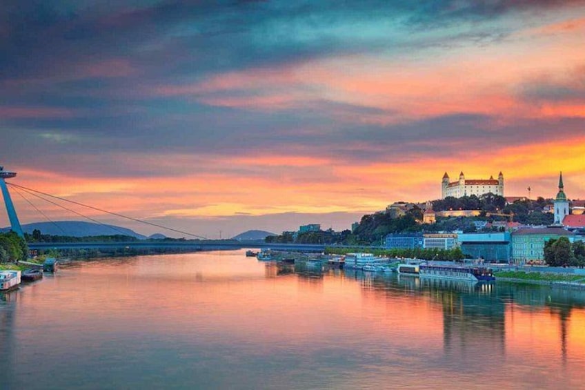 Ein Fluss mit Booten, eine Brücke und eine Burg auf einem Hügel bei Sonnenuntergang. 2