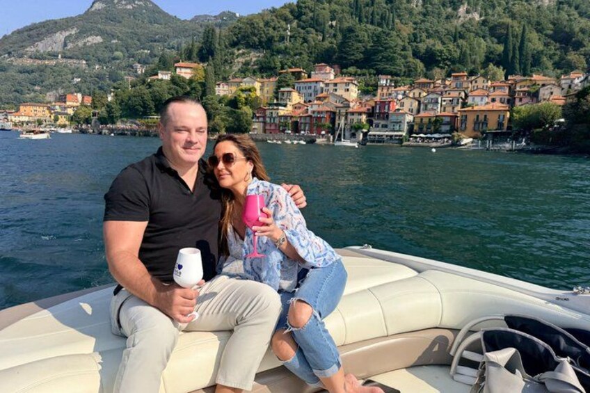 A couple on a boat with a lake and colorful buildings in the background. 4