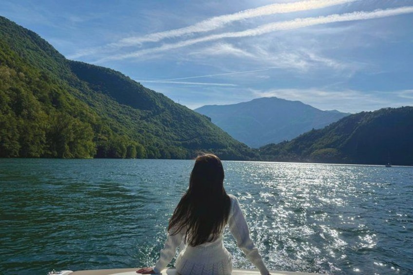 A person on a boat with a lake and mountains in the background. 1