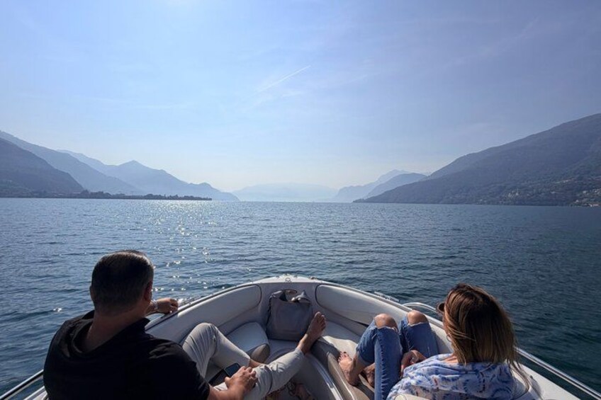 A boat with three people on a calm lake surrounded by mountains. 5