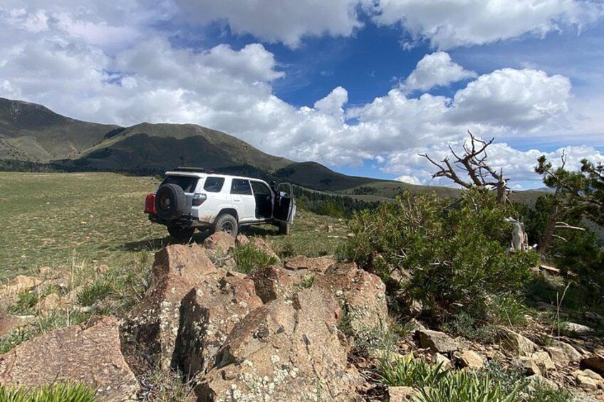 A white SUV parked on a rocky terrain with a mountainous landscape in the background. 3