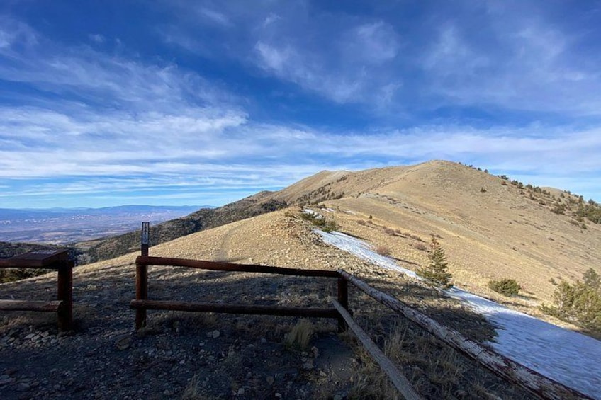 A wooden fence, a dirt path, and a hilly landscape with sparse vegetation. 2