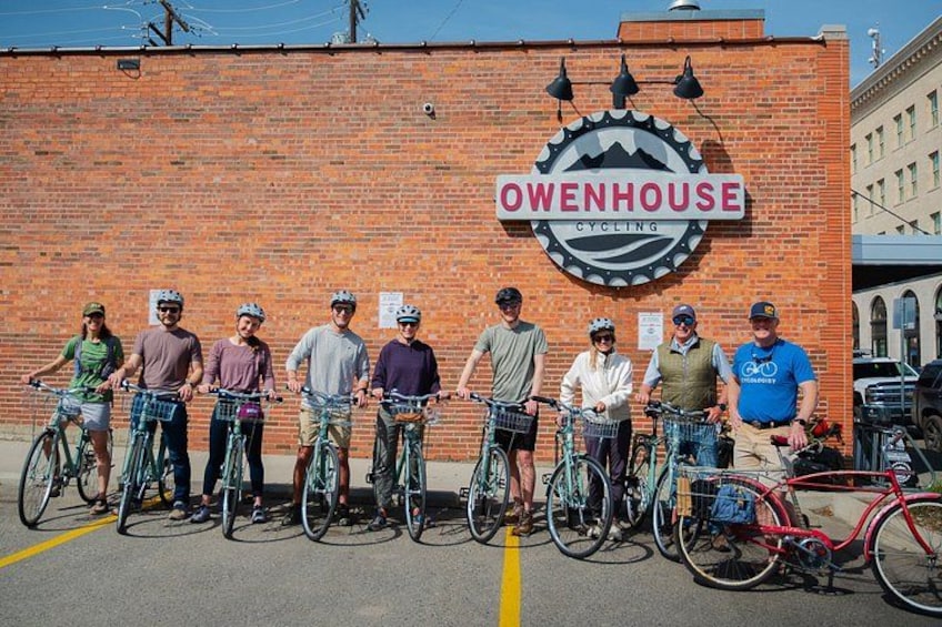 A group of cyclists standing in front of a brick wall with a sign that reads 'OWENHOUSE CYCLING.' 3