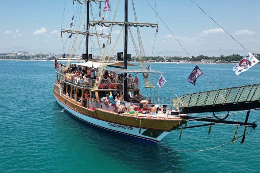 A wooden boat with multiple masts and flags, floating on a body of water. 3