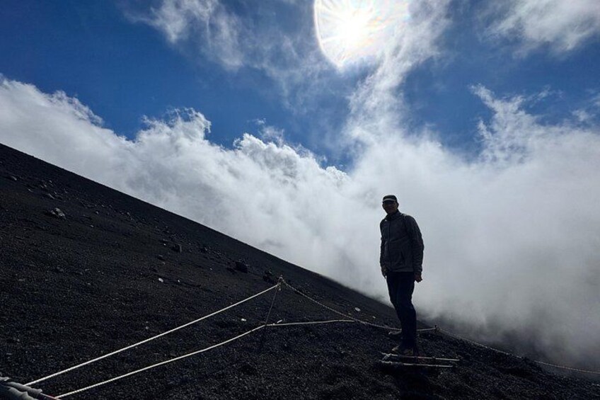 Una persona de pie en la cima rocosa de una montaña, con una cuerda, bajo un cielo parcialmente nublado. 4