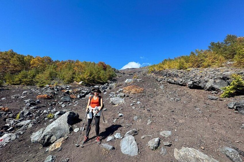 Un excursionista en un sendero pedregoso con follaje otoñal y cielo despejado. 2